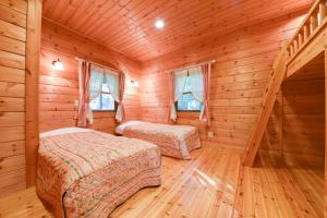 1 dormitorio con 2 camas en una cabaña de madera en Shurin, en Tsumagoi
