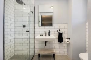 a white bathroom with a sink and a mirror at Manhattan On Coral Apartments in Bloubergstrand