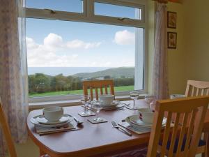 a table with plates and glasses and a large window at Arforwest in Llangranog