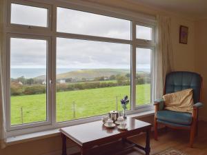 a living room with a large window with a table and a chair at Arforwest in Llangranog