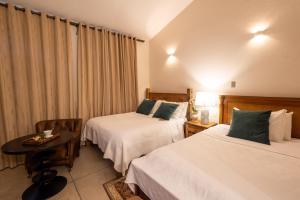 Cette chambre comprend 2 lits et une table. dans l'établissement Pousada Pequena Tiradentes, à Tiradentes