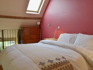 a bedroom with a white bed with a red wall at Little Burcott Loft in Wookey