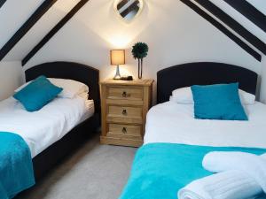 a bedroom with two beds and a table with a lamp at Wee Dug Hoose in Glenluce