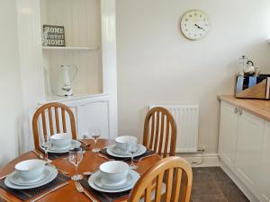 a dining room table with chairs and a clock on the wall at Tree Tops in Youlgreave