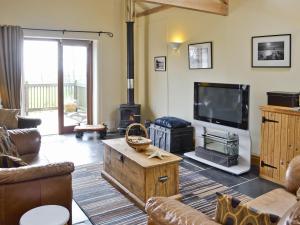 a living room with a couch and a tv and a fireplace at The Linhay in Milford