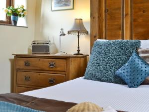 - une chambre avec un lit doté d'un oreiller bleu et d'une commode dans l'établissement The Linhay, à Milford