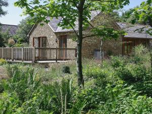 a brick house with a wooden deck in a garden at The Linhay in Milford