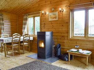 a living room with a fireplace in a log cabin at The Larches - E4651 in Mainstone