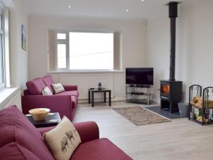 a living room with purple couches and a wood stove at Ty Howton in Clydach