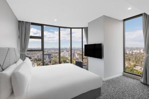 pokój hotelowy z łóżkiem i telewizorem w obiekcie Meriton Suites George Street, Parramatta w mieście Sydney