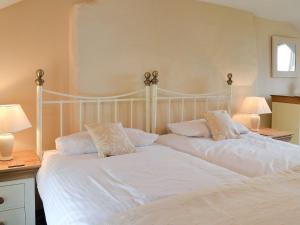 a bedroom with two beds with white sheets and pillows at Bryntrisant in Devils Bridge