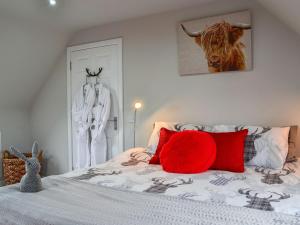 a bedroom with a bed with a red pillow on it at The Snug in Harthill