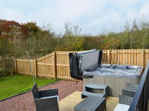 a backyard with a hot tub on a fence at The Snug in Harthill