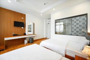 ein Hotelzimmer mit 2 Betten und einem Flachbild-TV in der Unterkunft Lotus Airport Hotel Saigon in Ho-Chi-Minh-Stadt