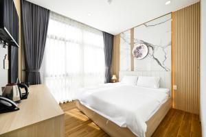 Un dormitorio con una gran cama blanca y una ventana en Lotus Airport Hotel Saigon en Ho Chi Minh