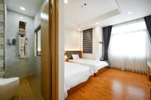 a bedroom with two beds and a shower and a toilet at Lotus Airport Hotel Saigon in Ho Chi Minh City