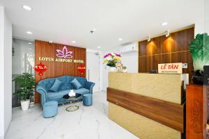 a lobby with a blue chair and a reception desk at Lotus Airport Hotel Saigon in Ho Chi Minh City