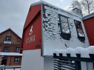 a building covered in snow next to a house at Stajnia in Szklarska Poręba