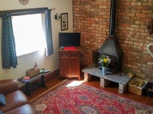 uma sala de estar com um sofá e uma lareira em The Shepherds Bothy em Tetford
