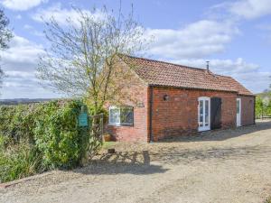 a brick cottage with a tree in front of it at The Shepherds Bothy in Tetford