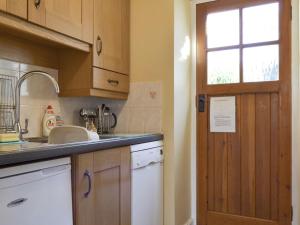 cocina con fregadero, ventana y puerta en Causey View, en Keswick