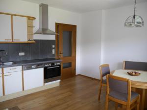 a kitchen with white cabinets and a table with chairs at Ferienwohnung Enn in Neukirchen am Großvenediger