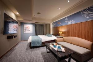 横浜市にあるHotel WILL BASE 旧Chamberyのベッドとソファ付きのホテルルーム