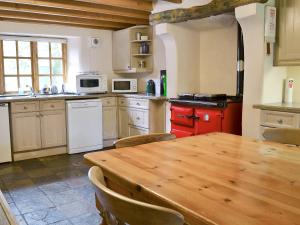 uma cozinha com uma mesa de madeira e um fogão vermelho em Brothersfield Cottage em Patterdale