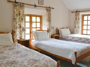 a bedroom with two beds and two windows at Brothersfield Cottage in Patterdale