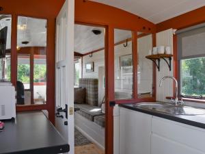 a kitchen with a sink and a living room at The Guards Van in Wetheringsett