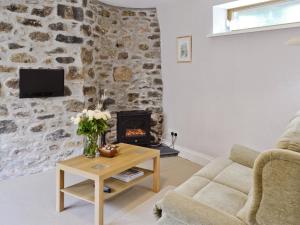 a living room with a stone wall and a fireplace at The Blacksmiths Shop in Lanlivery