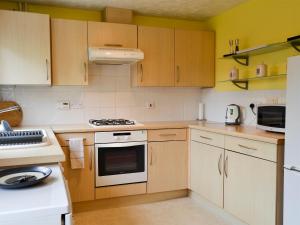 a kitchen with white appliances and wooden cabinets at Marina View in East Cowes