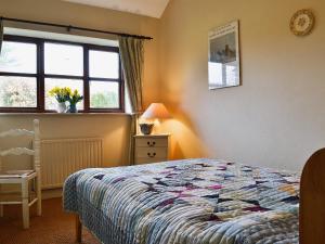 a bedroom with a bed and a window at The Linhay in Trewen