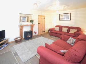 a living room with a red couch and a fireplace at Bramble Cottage - 27978 in Whalley