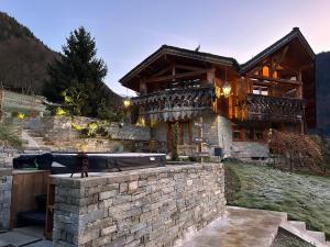 a large wooden house with a stone wall at Lodge Jardin Secret - Propriétés Mont Amour in Montriond