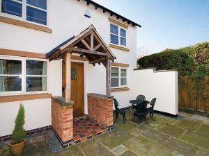 a detached house with a wooden door and a patio at Brook House Farm Cottage in Church Minshull