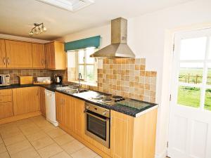 uma cozinha com armários de madeira e um forno com placa de fogão em Brook House Farm Cottage em Church Minshull