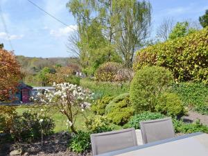 un jardín con sillas, flores y árboles en Bee Bowl Cottage - Httd, en Bideford