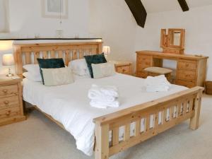 1 dormitorio con 1 cama grande de madera y toallas. en Bee Bowl Cottage - Httd, en Bideford