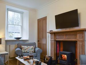 a living room with a fireplace and a tv at Coachmans Cottage in Falkland