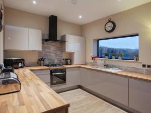 a kitchen with white cabinets and a clock on the window at One The Old Stables in Knitsley