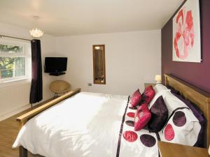 a bedroom with a large white bed with red pillows at Hidden Garden Cottage - E5543 in Wainfleet All Saints