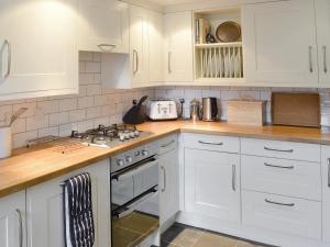 a kitchen with white cabinets and a stove top oven at Bucca Cottage in Newlyn