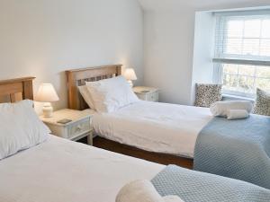 a bedroom with two beds and a window at Bucca Cottage in Newlyn