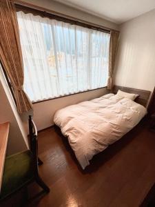 uma cama num quarto com uma grande janela em lifeone club em Hiroshima