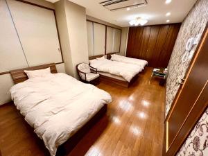 una habitación de hospital con 2 camas y una silla en lifeone club, en Hiroshima
