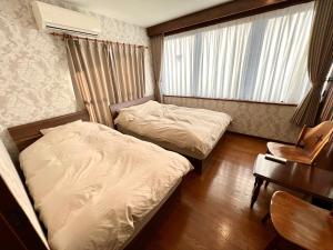 um quarto com 2 camas, uma secretária e uma cadeira em lifeone club em Hiroshima