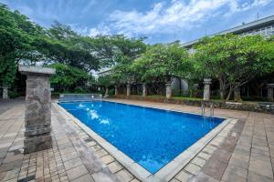 a large swimming pool in a yard with trees at Oakwood Hotel & Apartments Taman Mini Jakarta in Jakarta