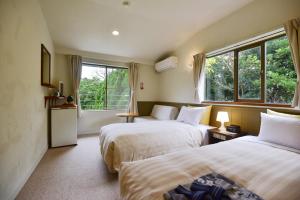 two beds in a room with two windows at Gardenvilla Shirahama in Shimoda