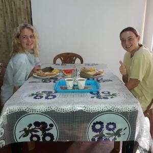 dos mujeres sentadas en una mesa con un plato de comida en Colonial Surfing Villa Hostel & Home Stay en Midigama